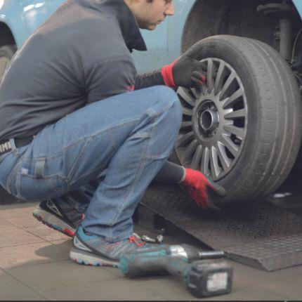 insurance for motor traders provides protection for customer as he replaces a tyre.
